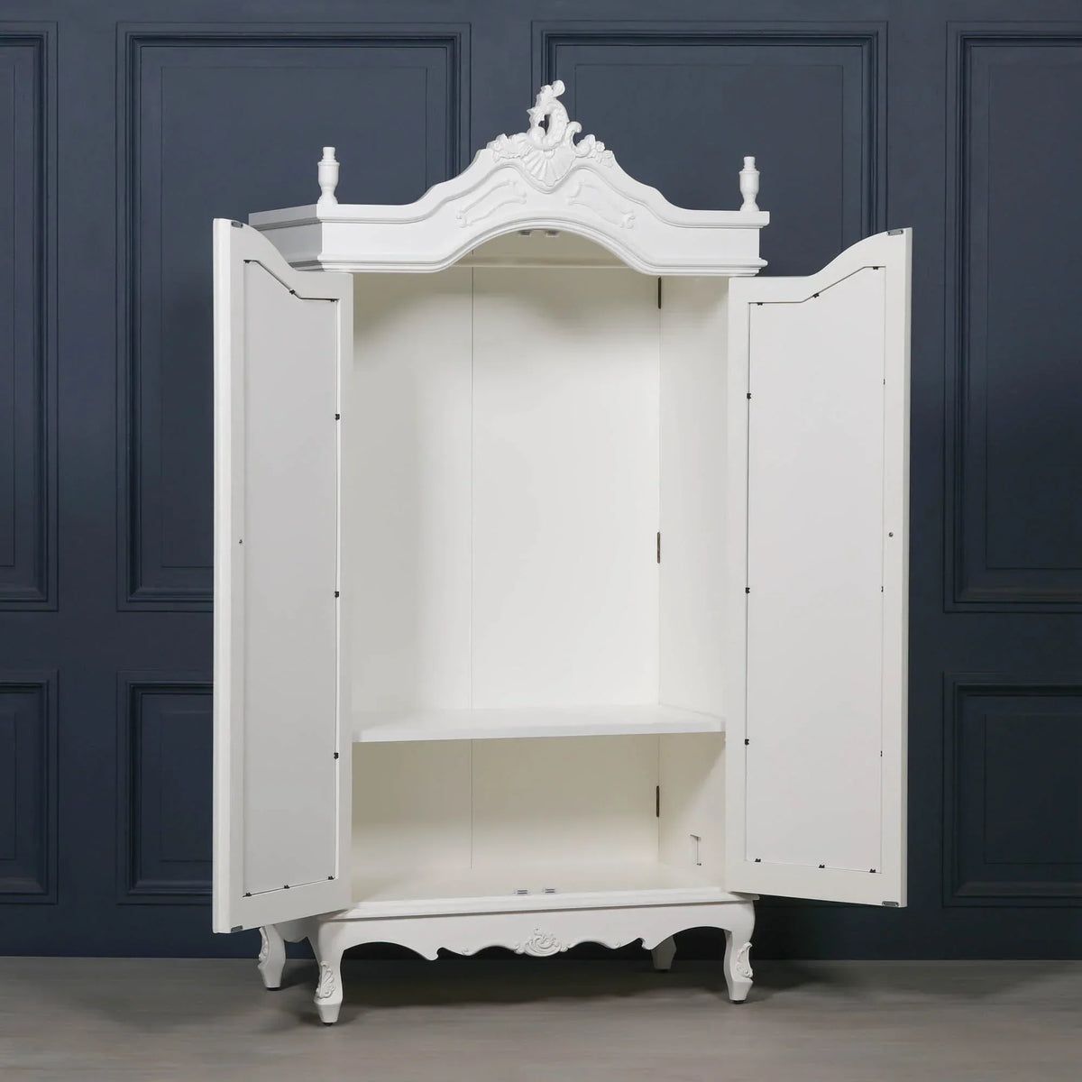 White wooden wardrobe with ornate detailing, open doors, and internal shelving
