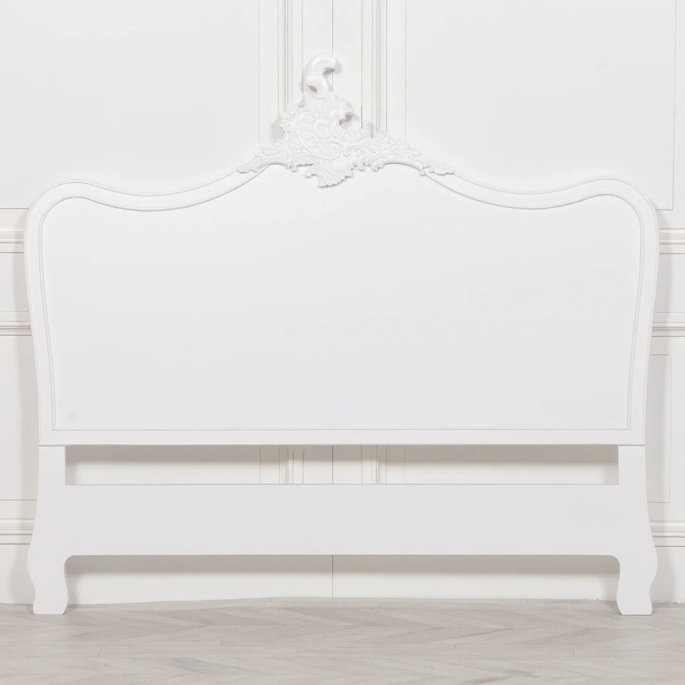 White wooden headboard with carved ornate detail and curved edges against wall paneling