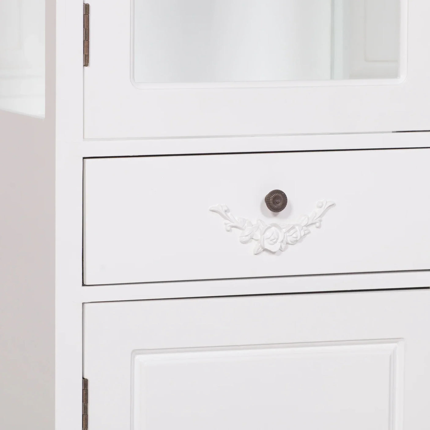 White wooden cabinet with floral drawer handle and metal knob detail
