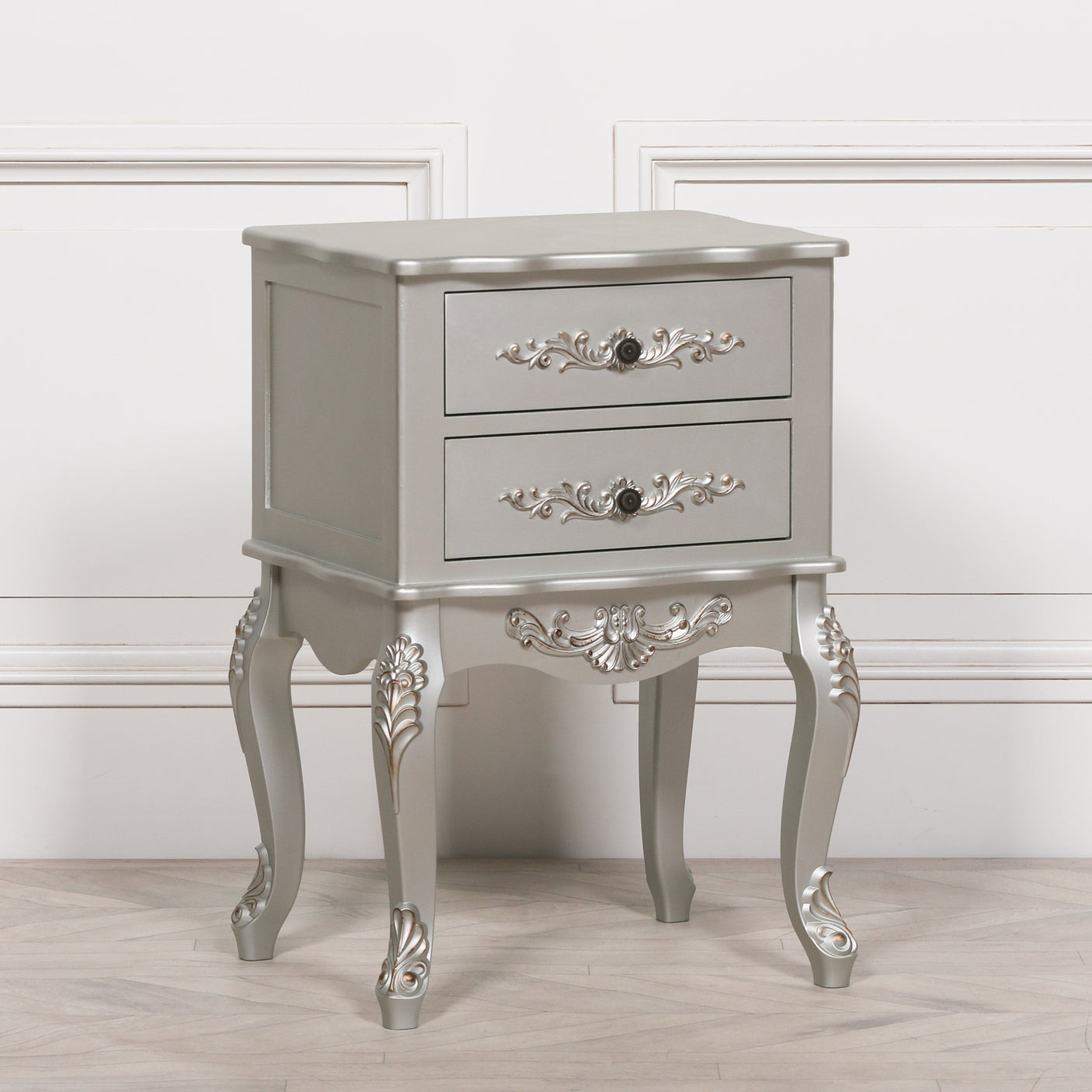 Silver bedside table with ornate carvings and two drawers on curved legs