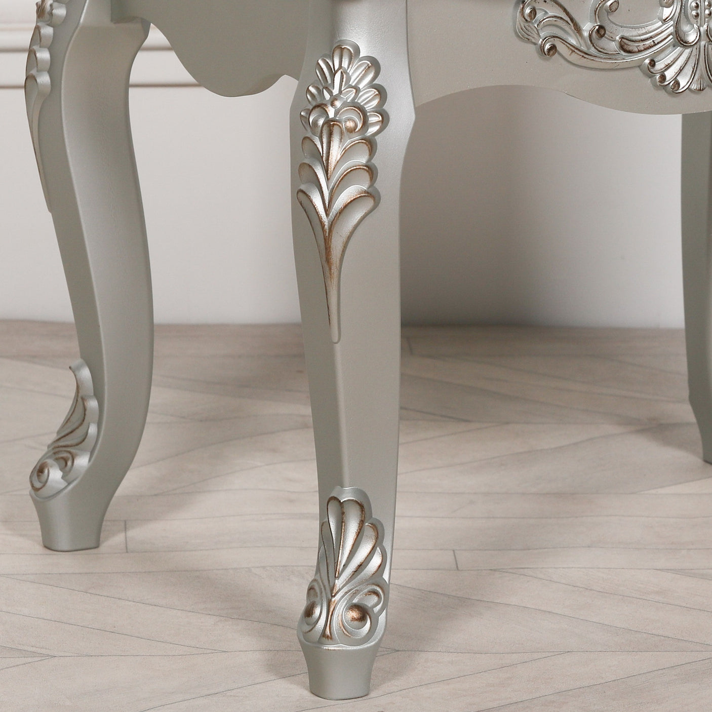 Silver painted furniture legs with ornate carved detailing on wooden floor