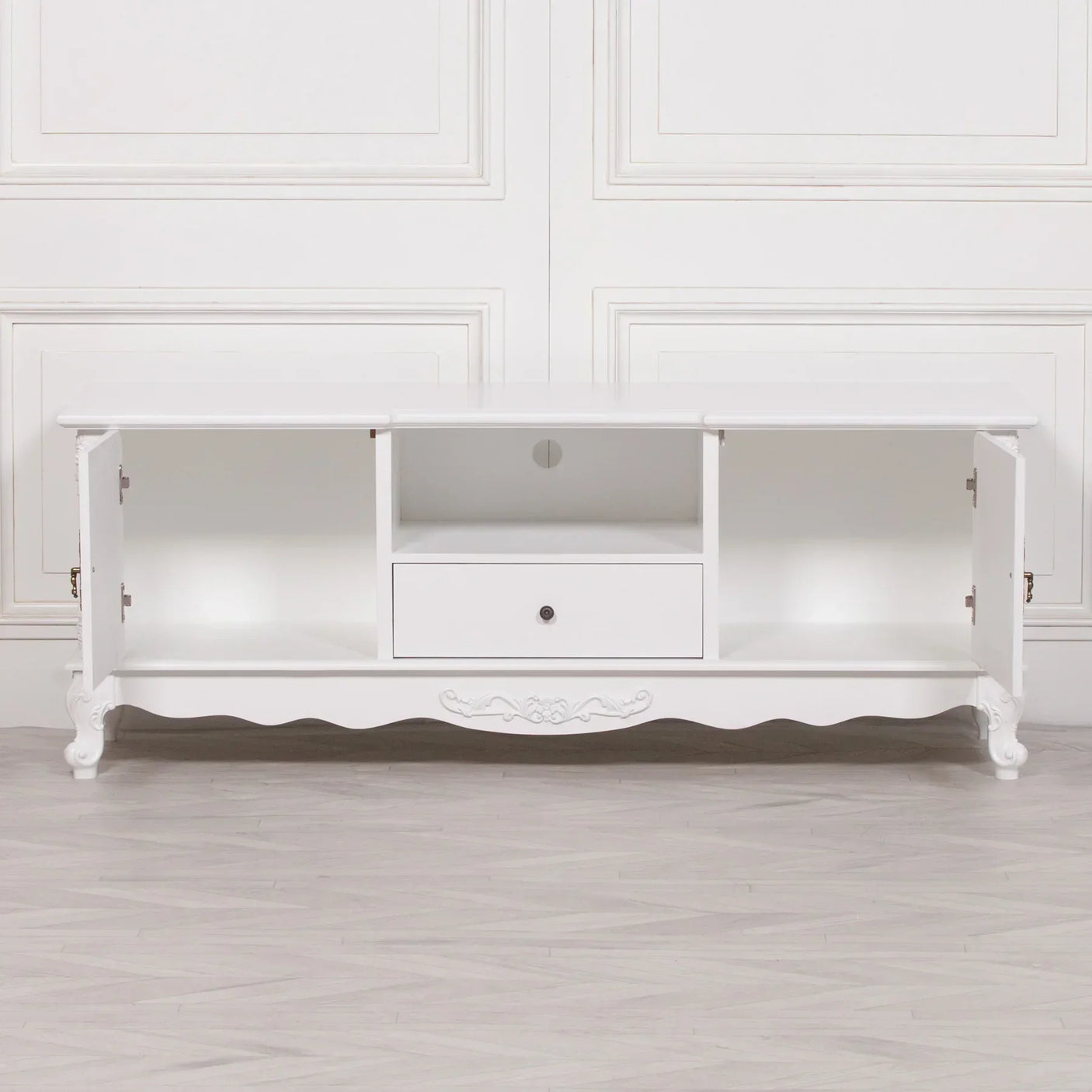 White wood TV unit with two open doors, central drawer and scalloped legs on light floor