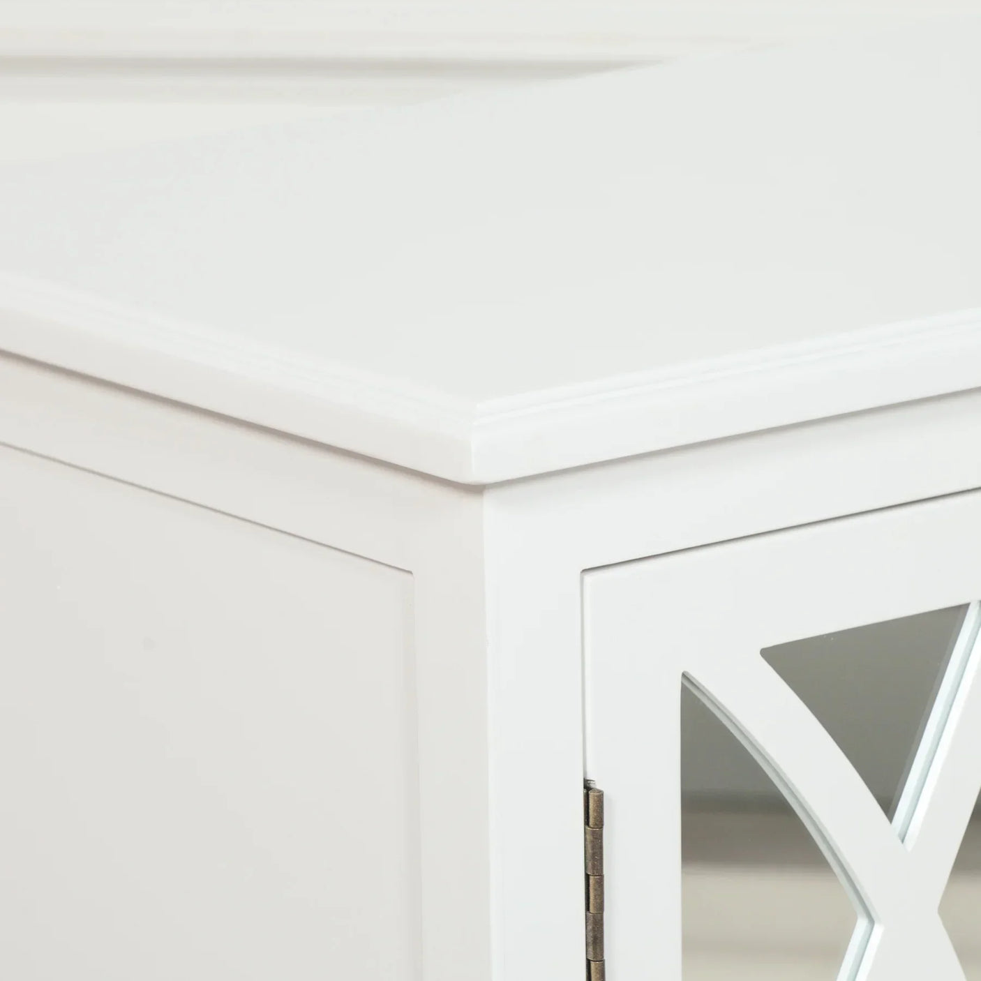 White wooden cabinet corner with mirrored door and decorative panel detail