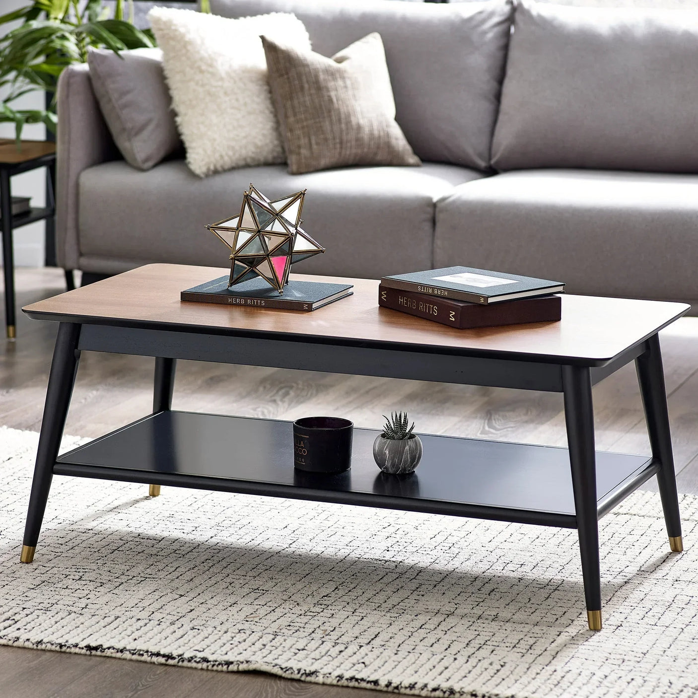 Modern wood coffee table with black legs and shelf, styled in living room with sofa and decor