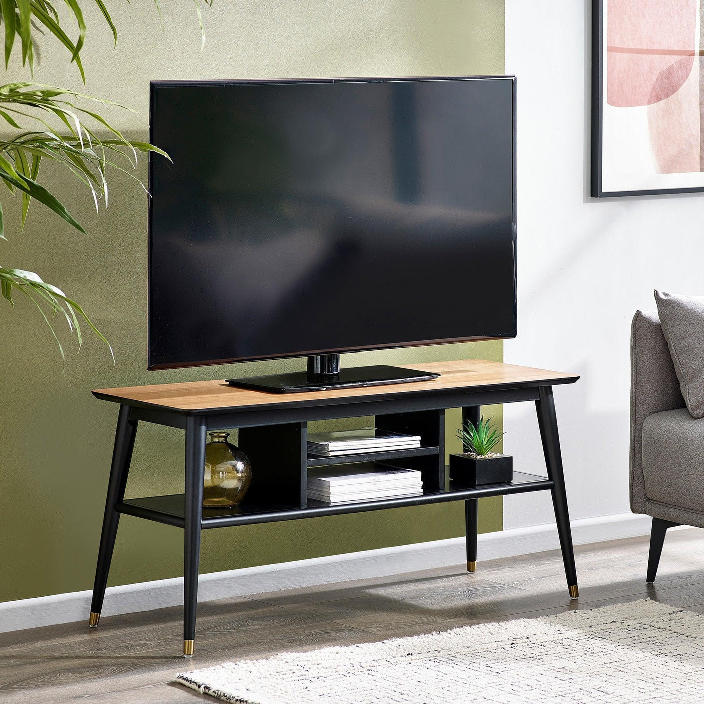 Wood and black TV stand with storage shelves, supporting large flat screen TV in living room