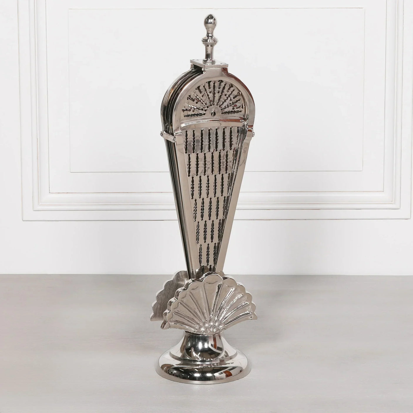 Silver metal firescreen with decorative fan design on round base, displayed upright