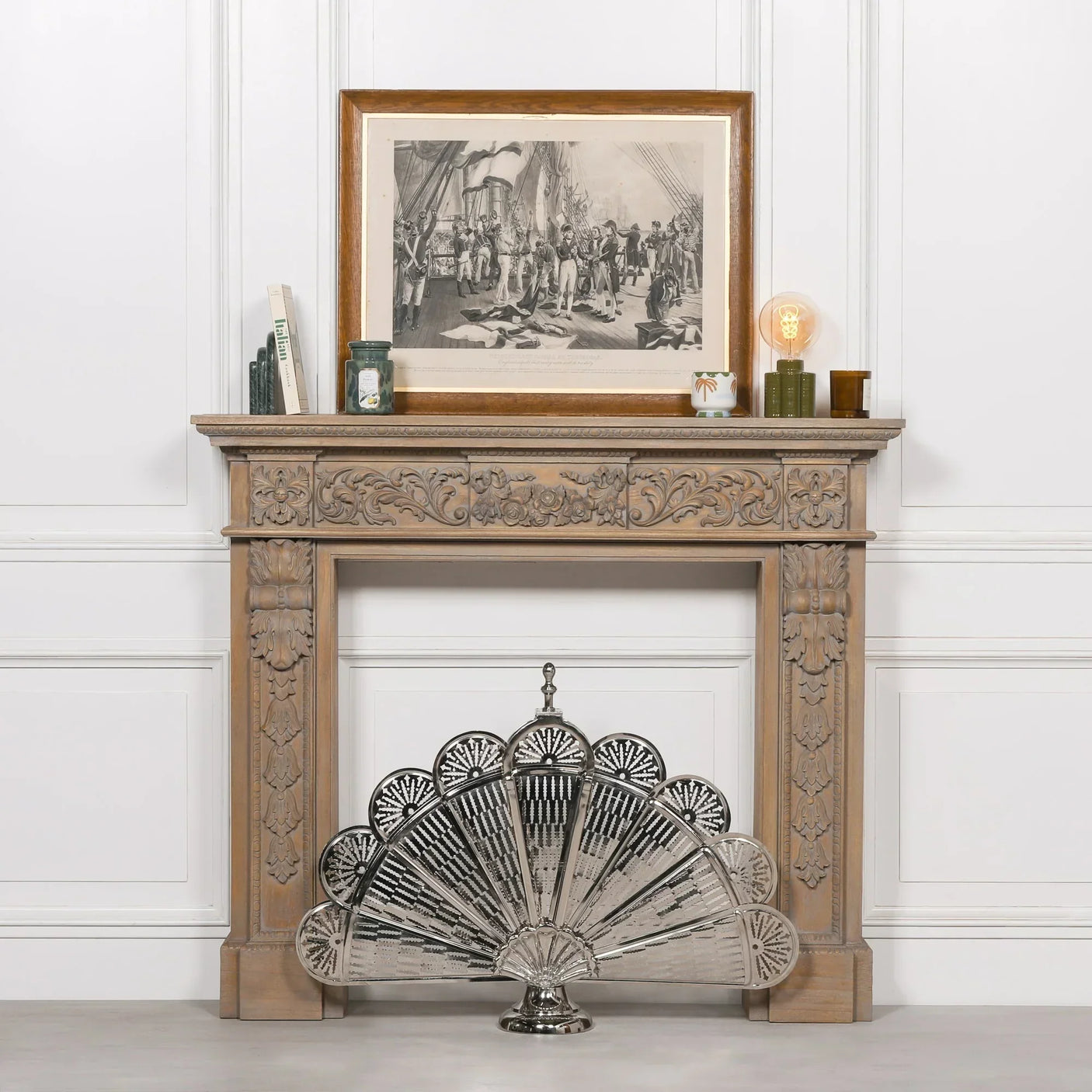 Silver metal firescreen with fan design in front of carved wood fireplace mantel