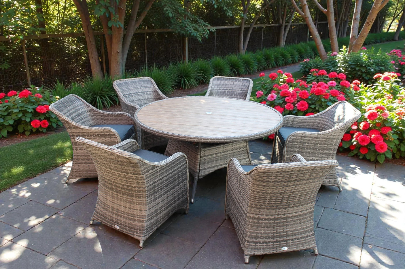 Rattan garden dining set with six cushioned chairs and round table on stone patio