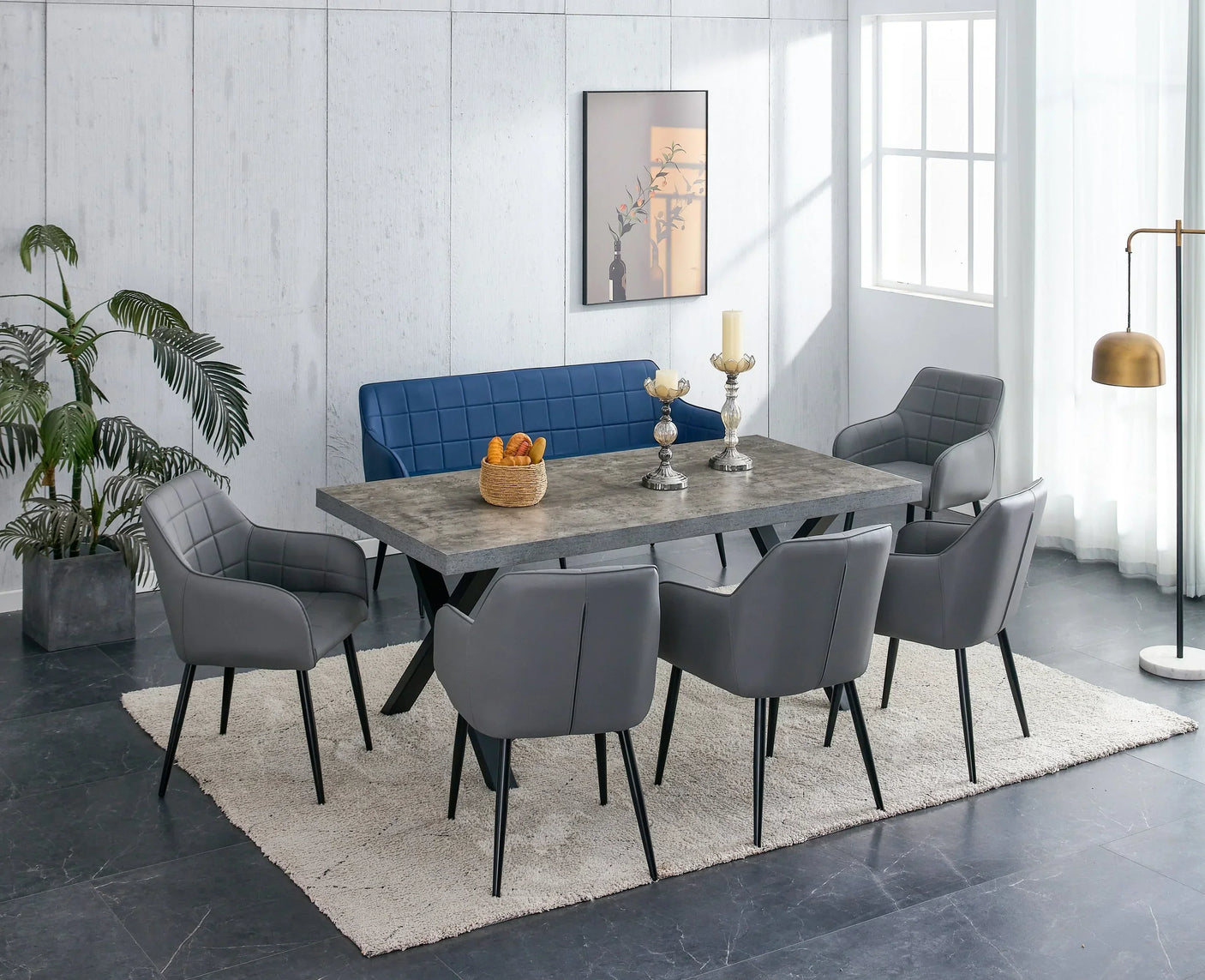 Grey dining table with X legs, grey chairs, and a blue bench on a light rug
