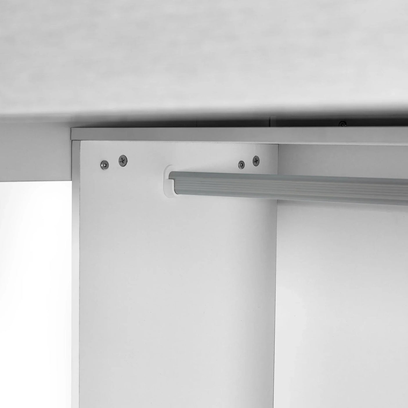 White wardrobe interior with horizontal hanging rail and metal hardware detail