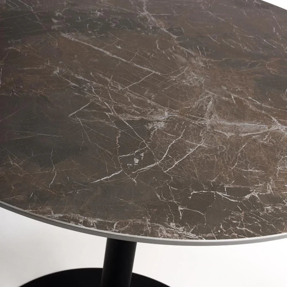 Round brown marble dining table top with black pedestal base close up