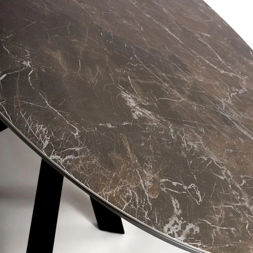 Round marble dining table top with grey and white veining, black angled legs visible