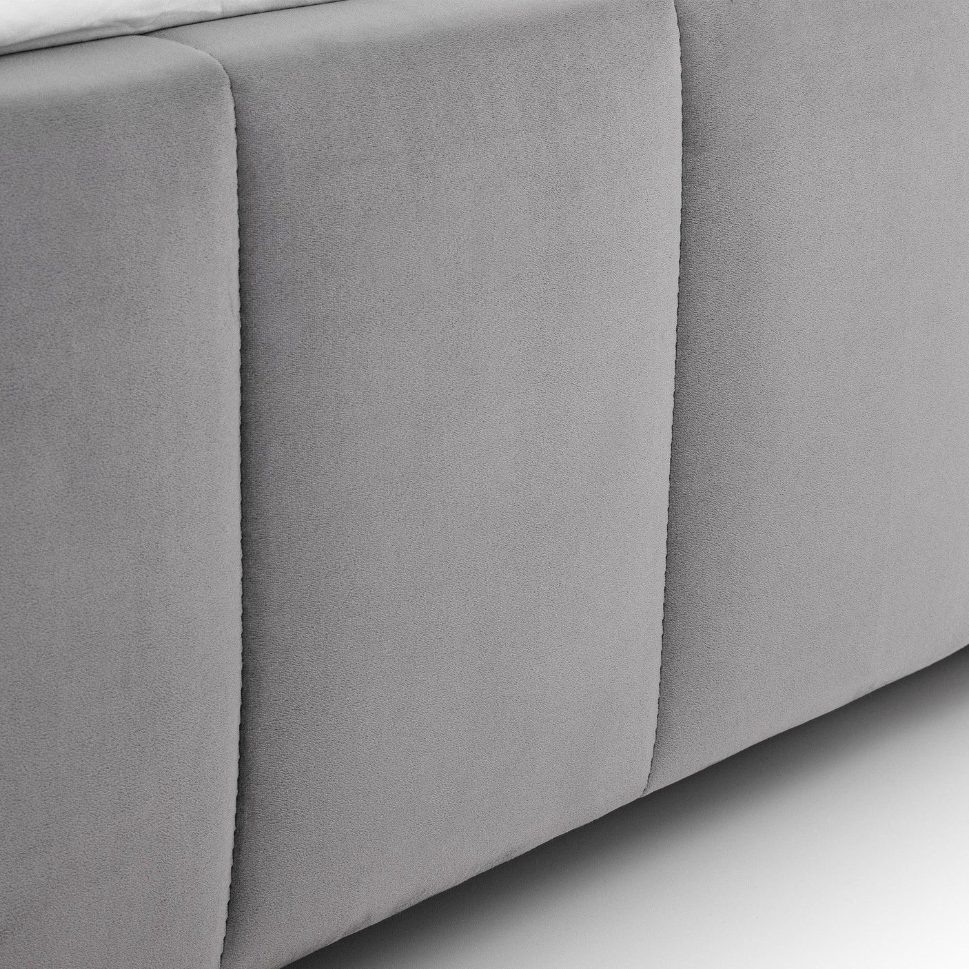 Close-up of grey fabric upholstered bed base with vertical stitching detail