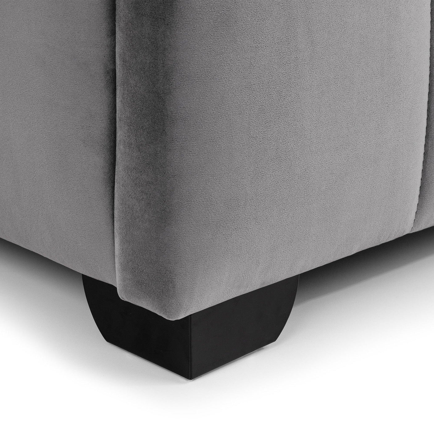 Close-up of grey bed frame corner with fabric upholstery and black wooden leg