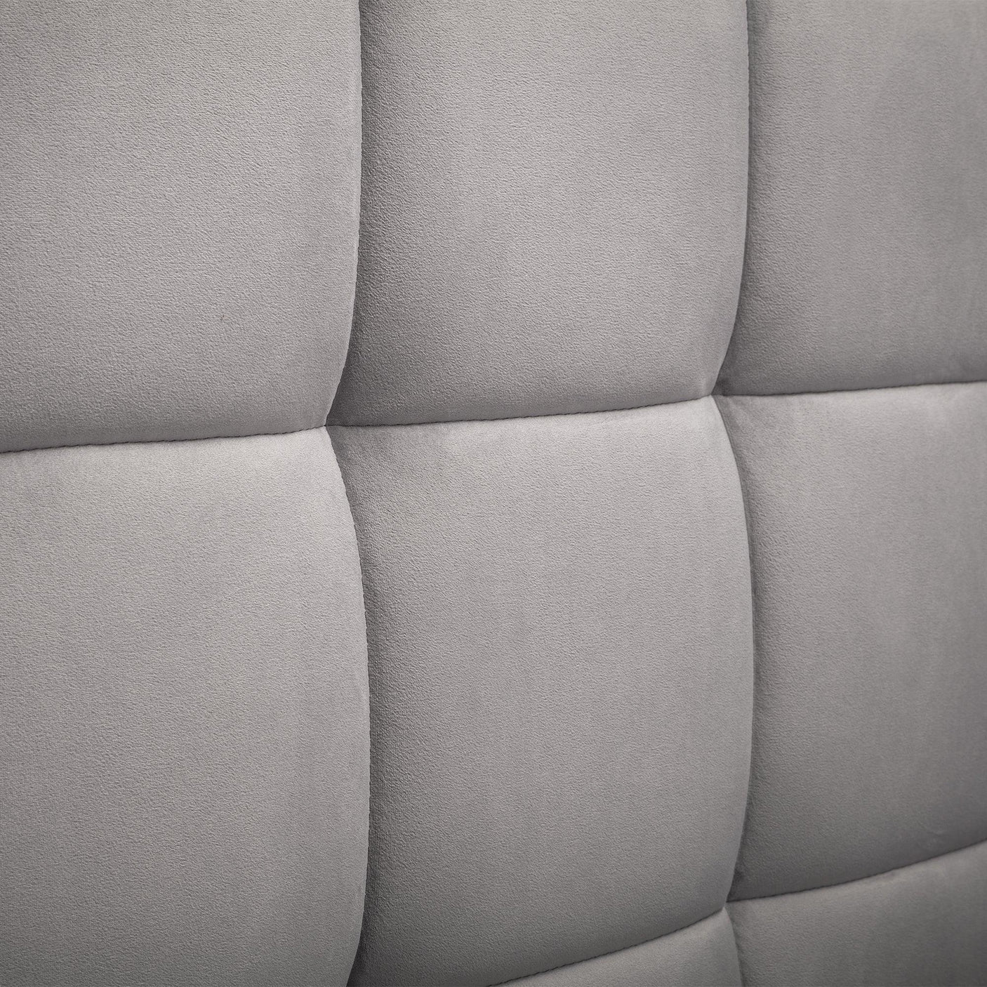 Close-up of grey fabric ottoman bed headboard with square stitched upholstery detail