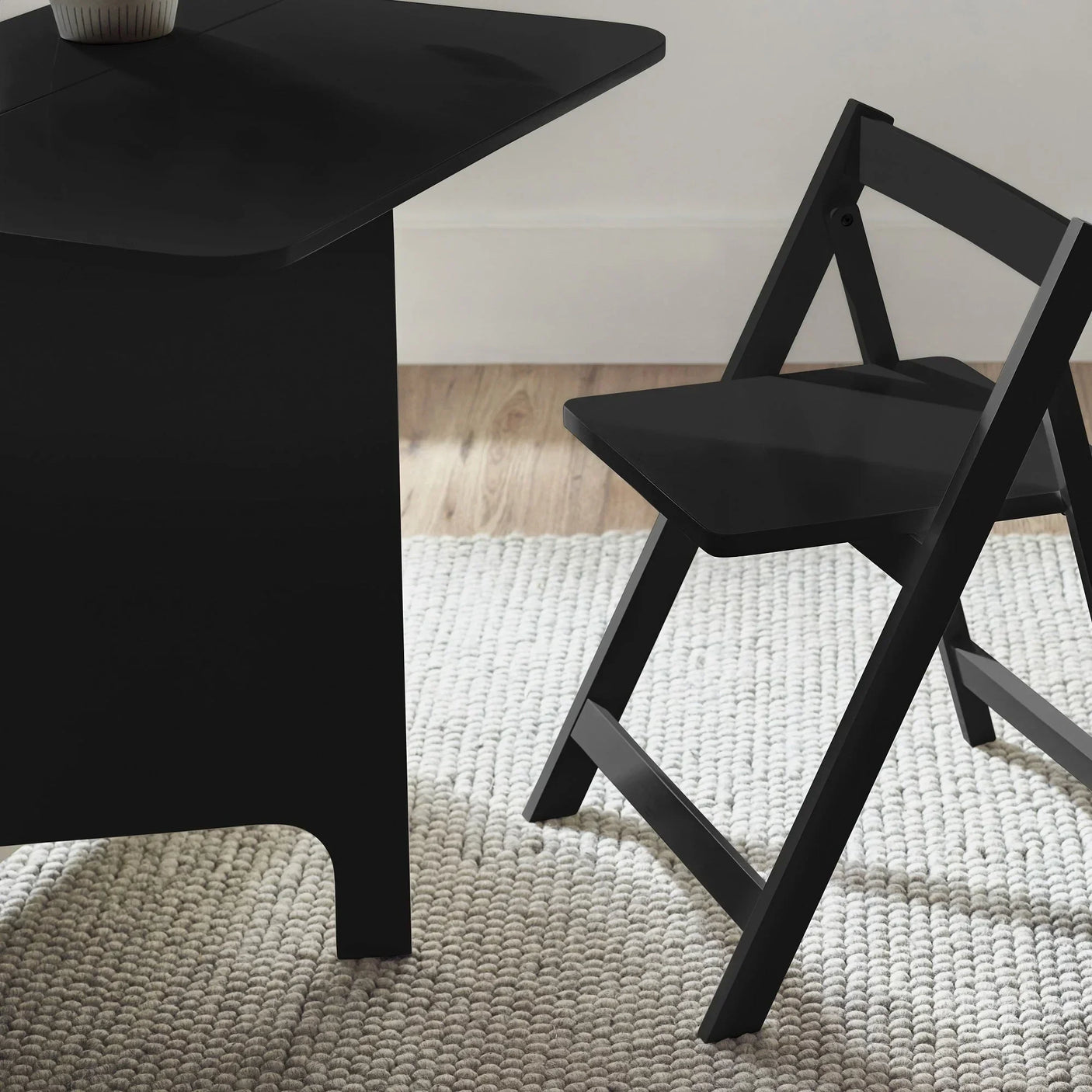 Black gateleg table and folding chair set on light textured rug