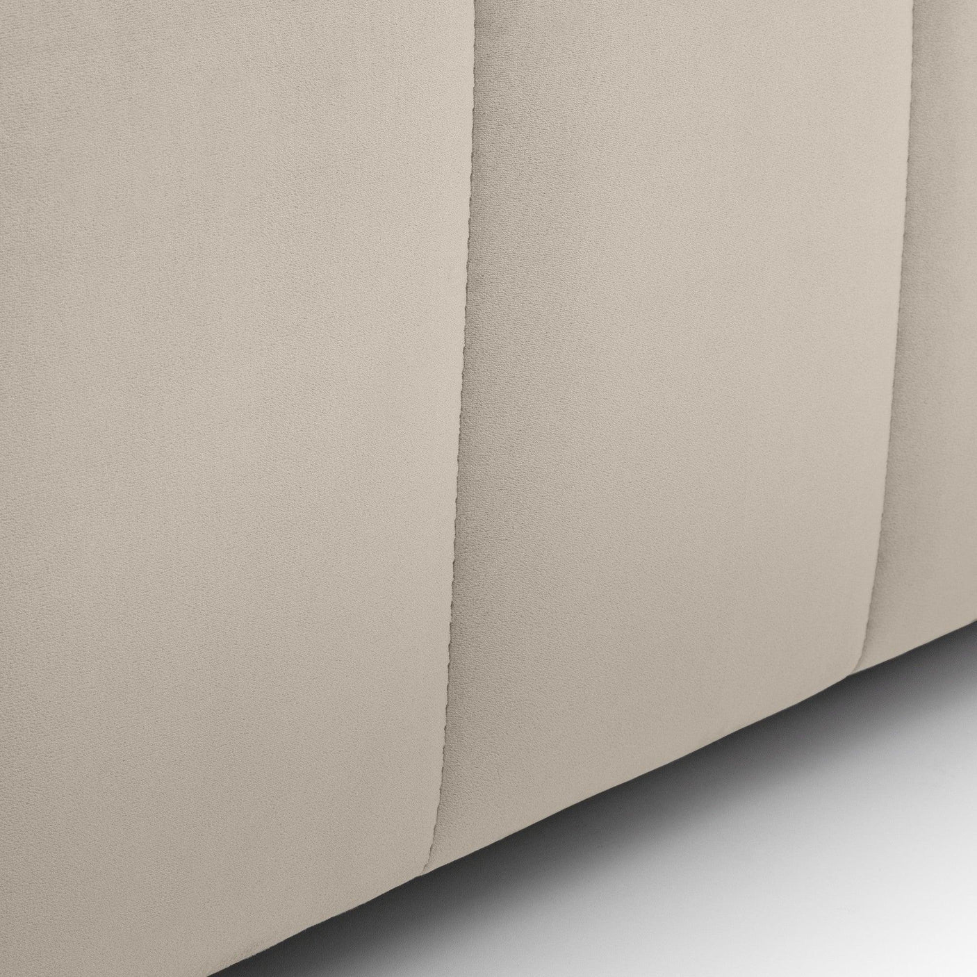Close-up of beige upholstered bed base fabric with vertical stitching detail
