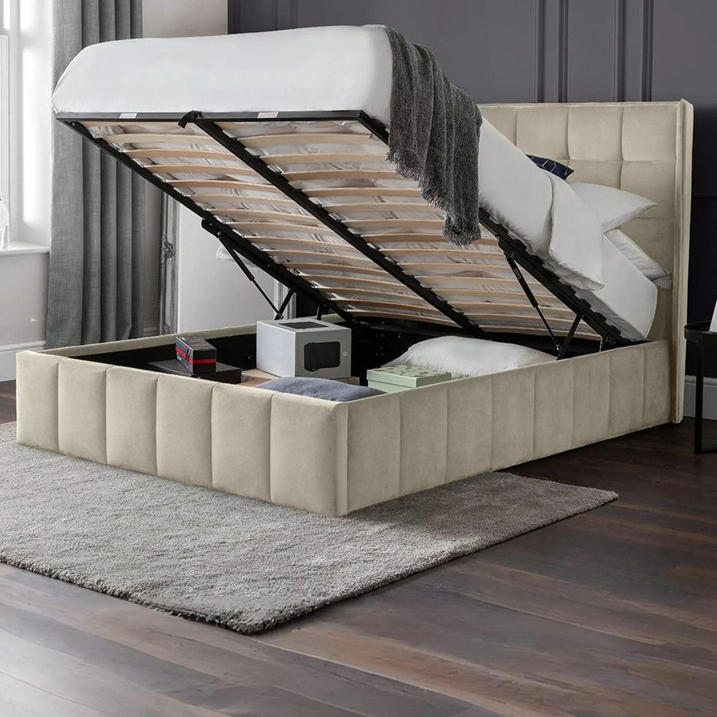 Beige ottoman storage bed with open lift-up base showing underbed storage compartments