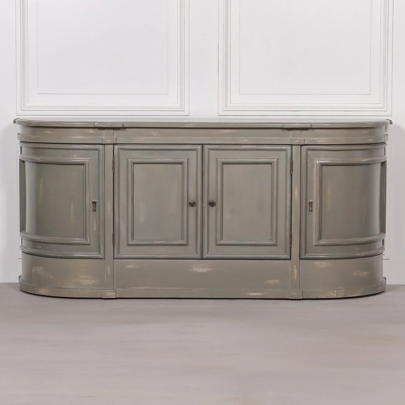 Grey wooden sideboard with curved ends and four paneled doors against white wall