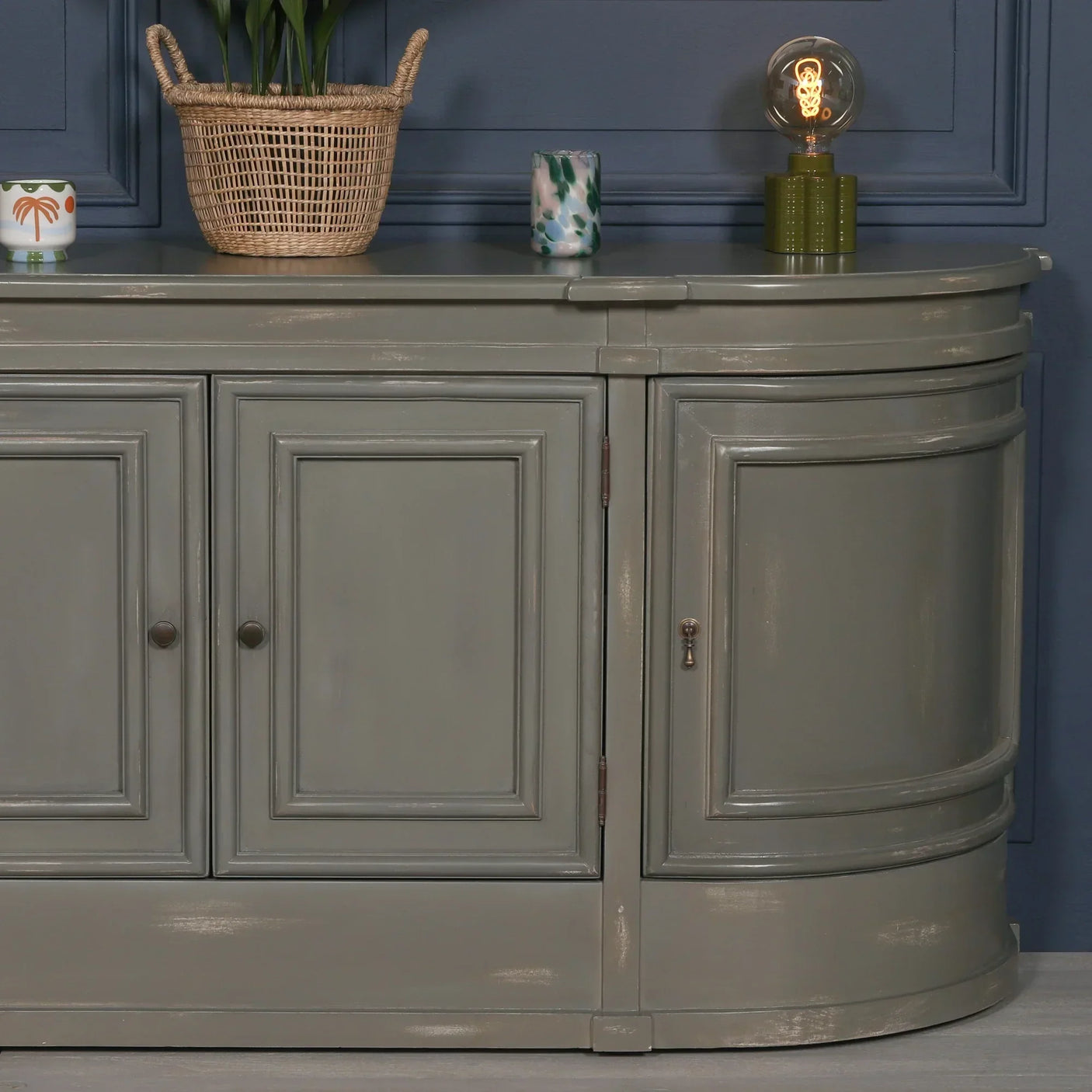 Grey painted sideboard cabinet with panel doors, basket and lamp decor on top