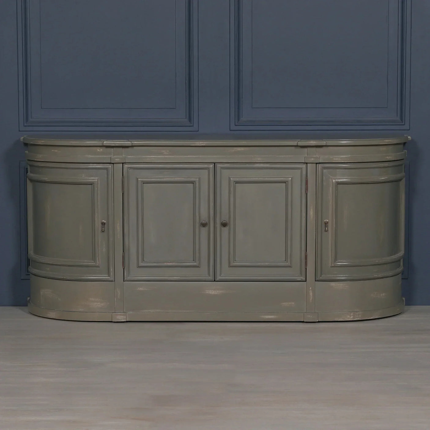 Grey painted sideboard with four paneled doors and curved ends against blue wall