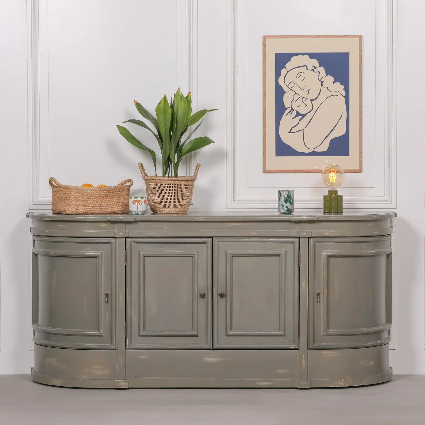 Grey wooden sideboard cabinet with curved edges and three panel doors in living room setting