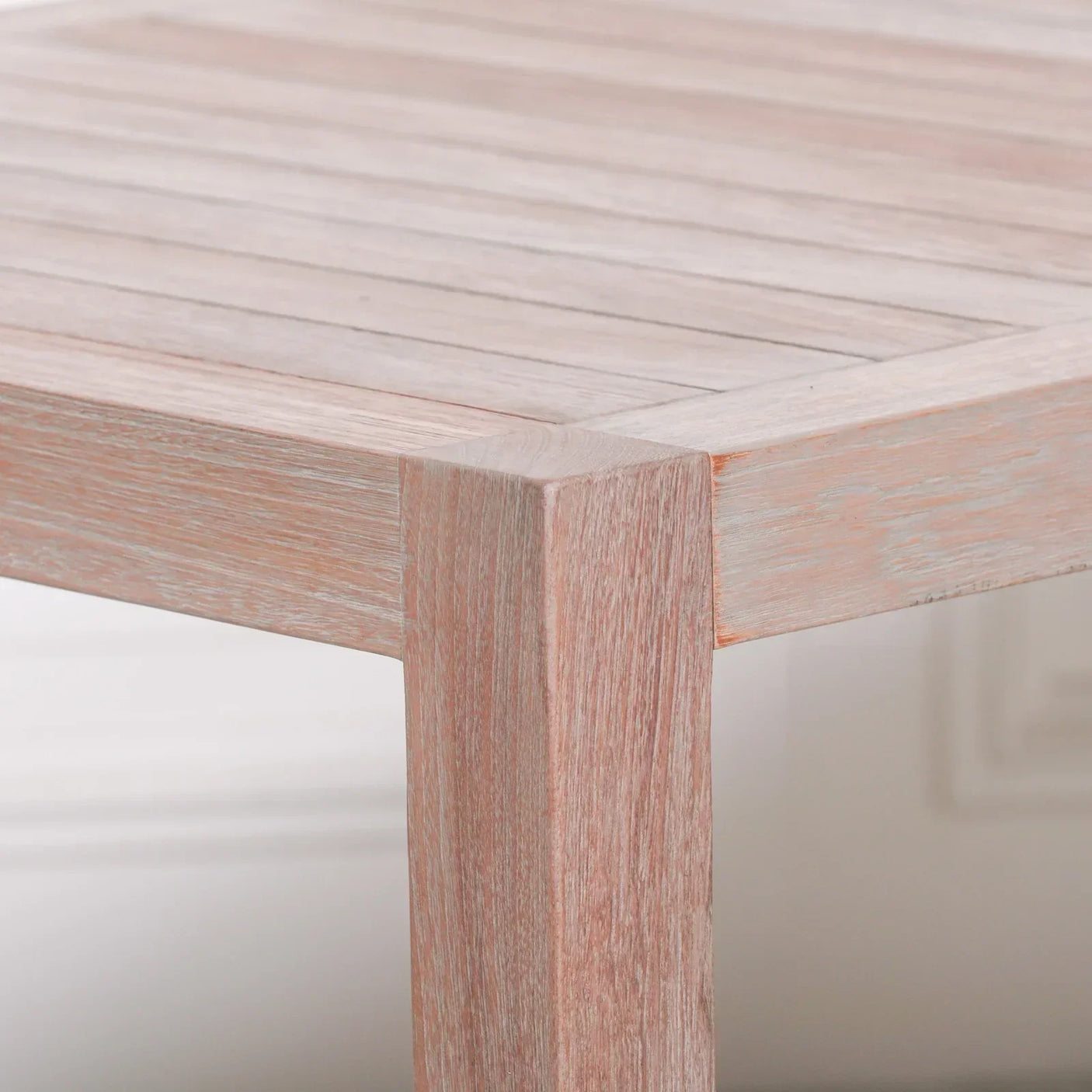 Corner detail of light wood dining table with visible grain and slatted top