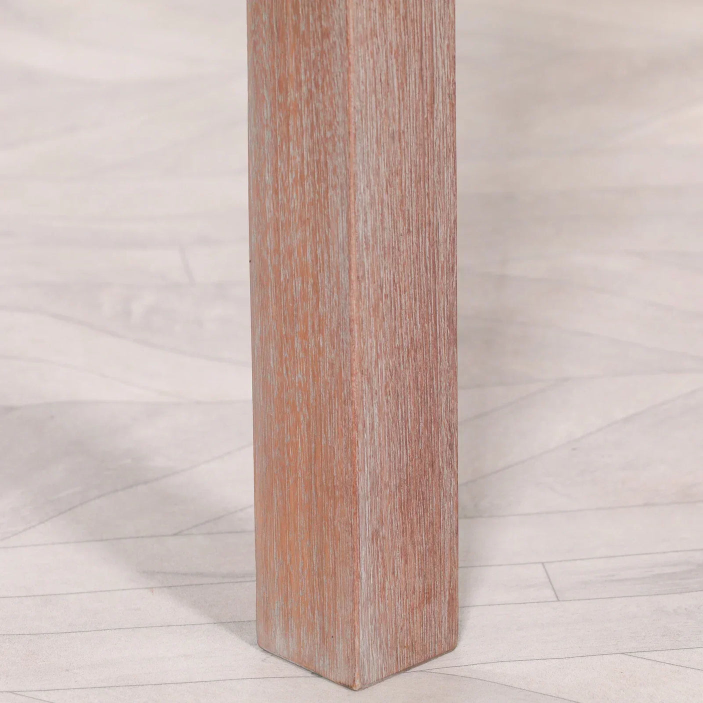 Close up of wooden furniture leg with light brown finish on pale wood flooring