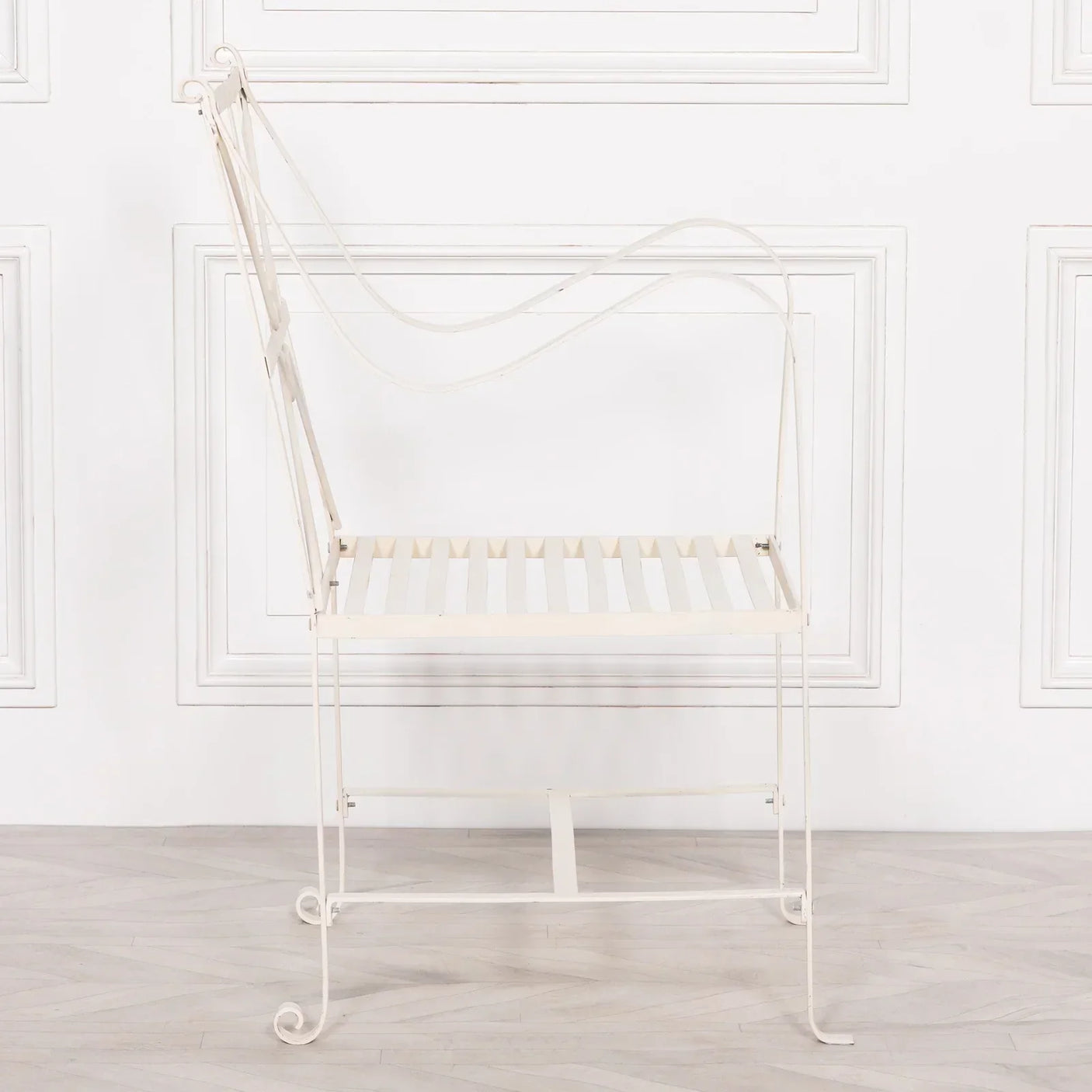 Cream metal garden chair with slatted seat and curved armrests, side view