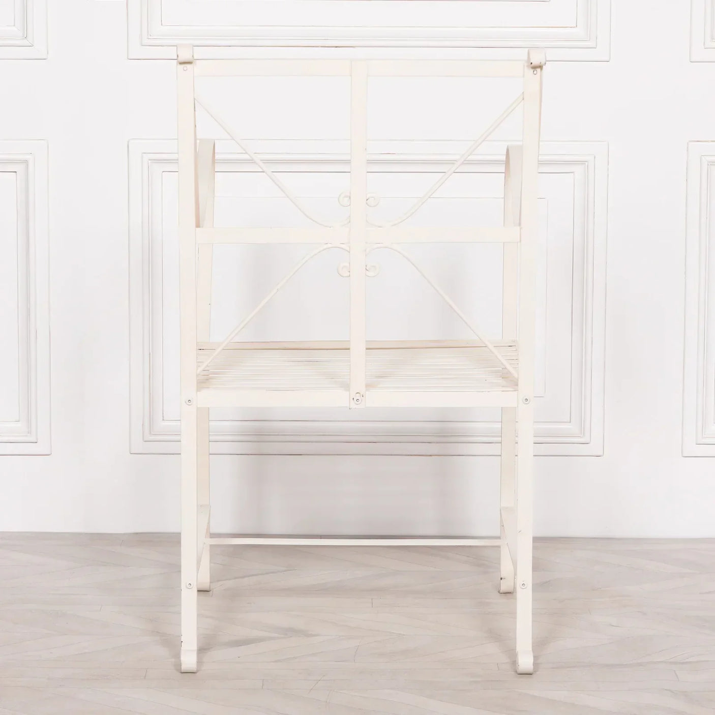 White metal dining chair with cross back design viewed from behind on wooden floor