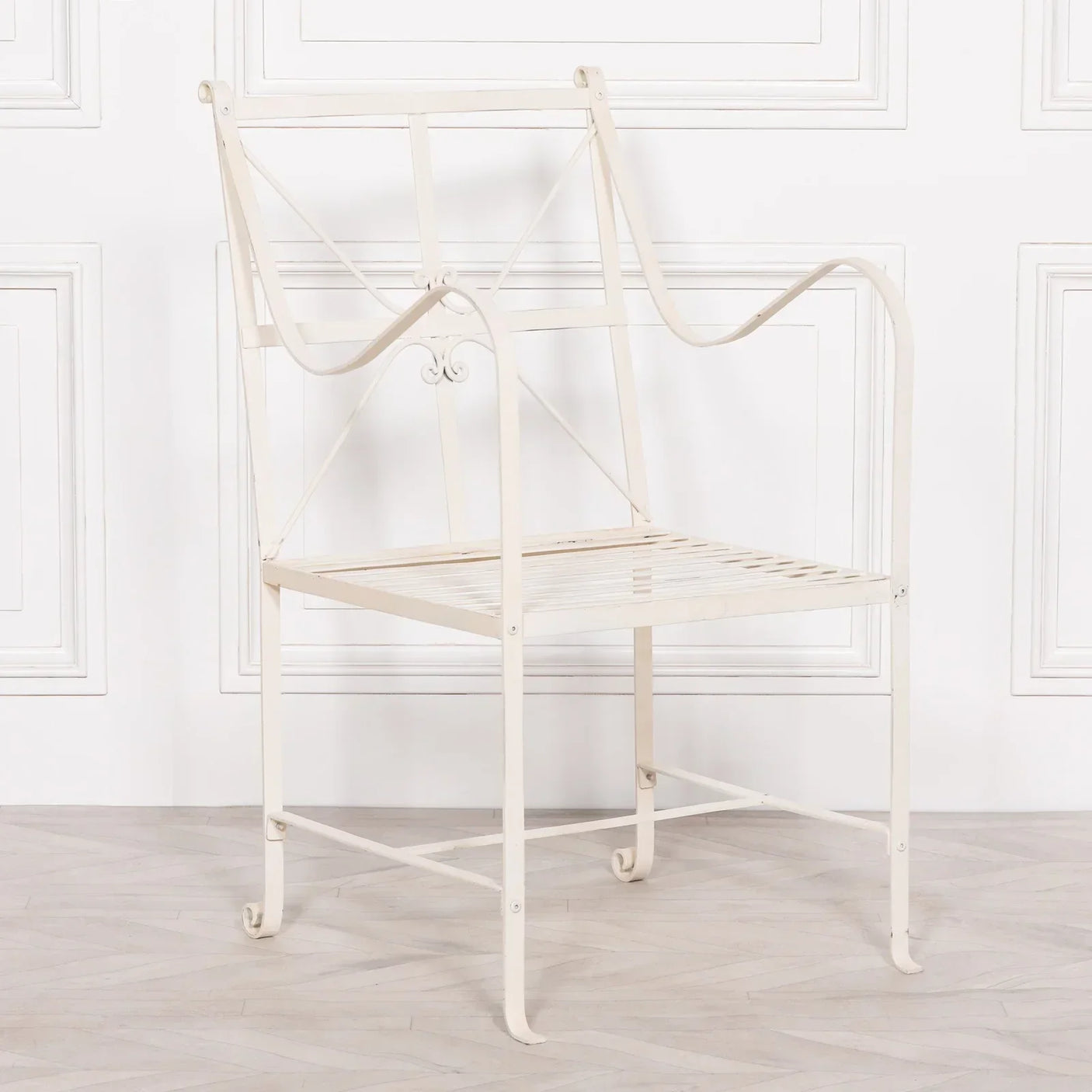 Cream metal dining chair with curved arms and decorative backrest against white wall