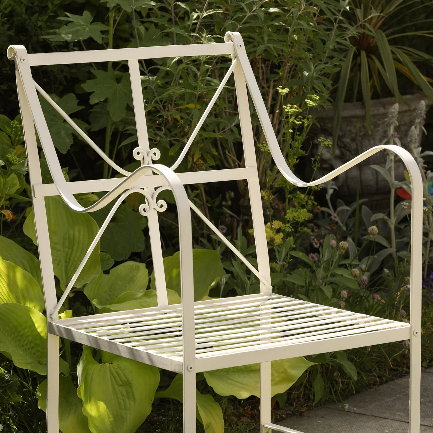 Cream metal garden chair with slatted seat and scroll armrests in outdoor patio setting