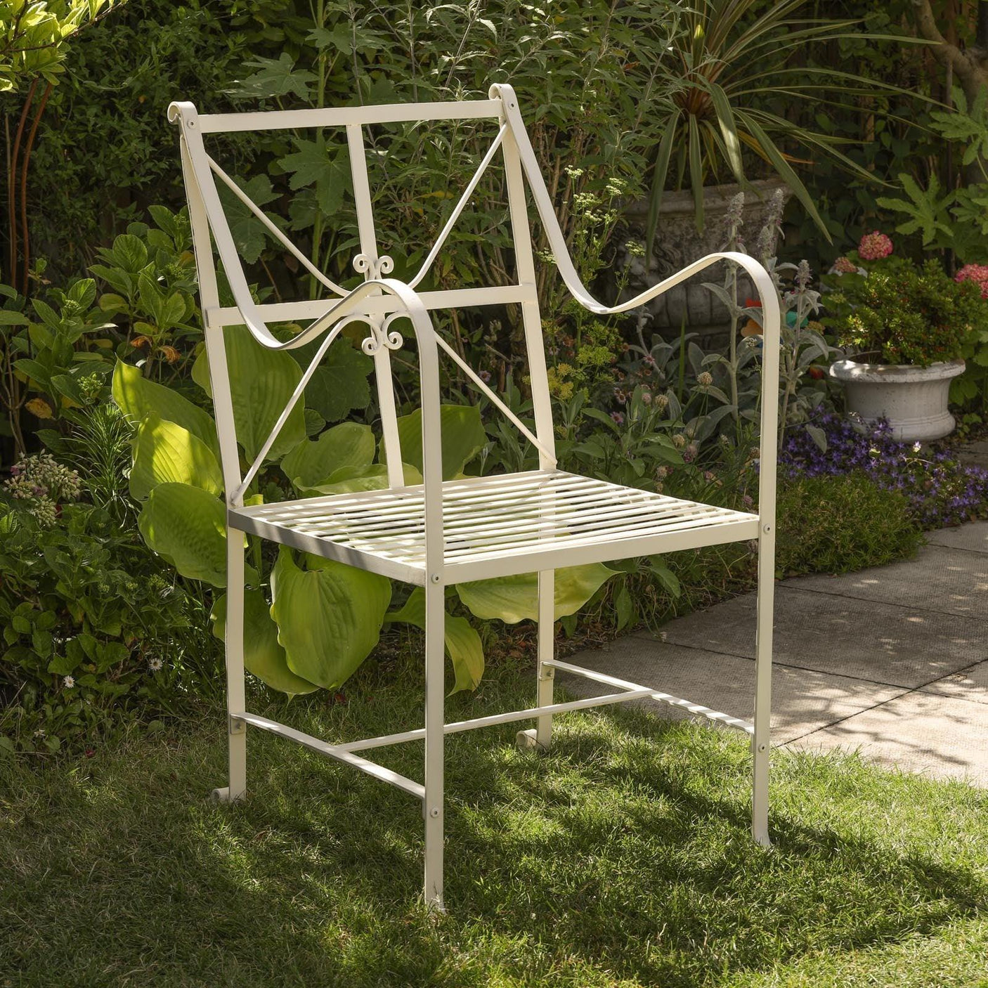 Cream metal garden chair with slatted seat and decorative arms on lawn