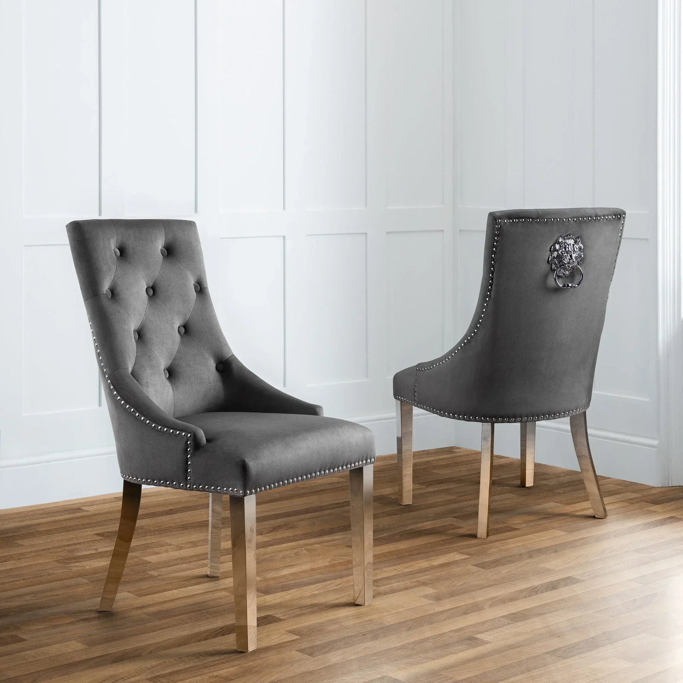 Grey velvet dining chair with button tufting and silver stud trim on wooden floor