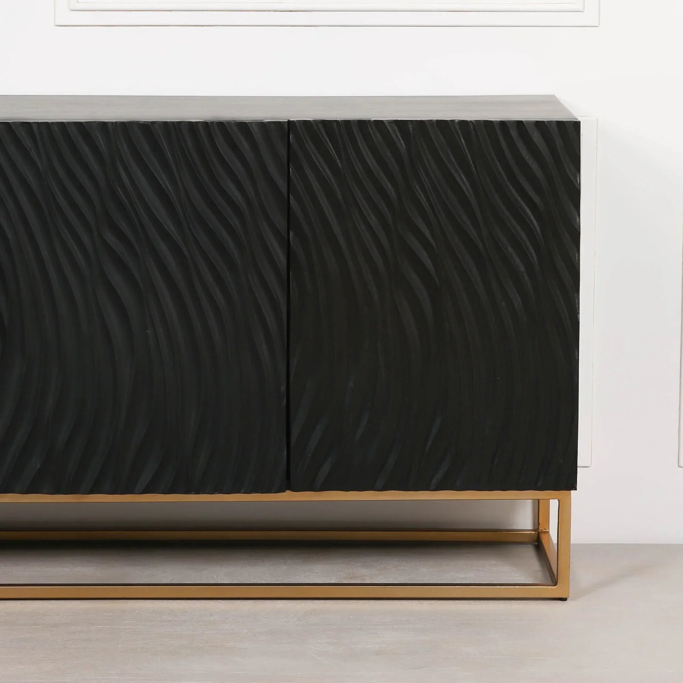 Black textured sideboard with wave pattern and gold metal base on light floor