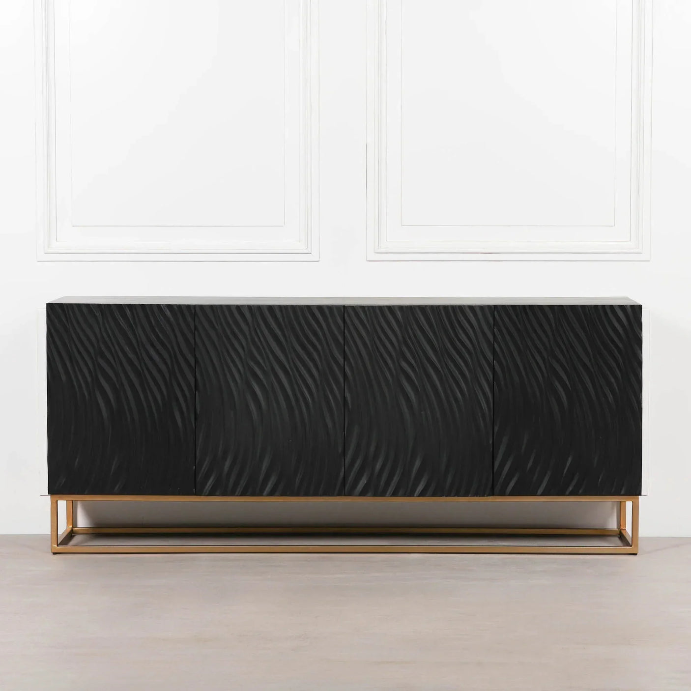 Black sideboard with textured wavy doors and gold metal base against white wall