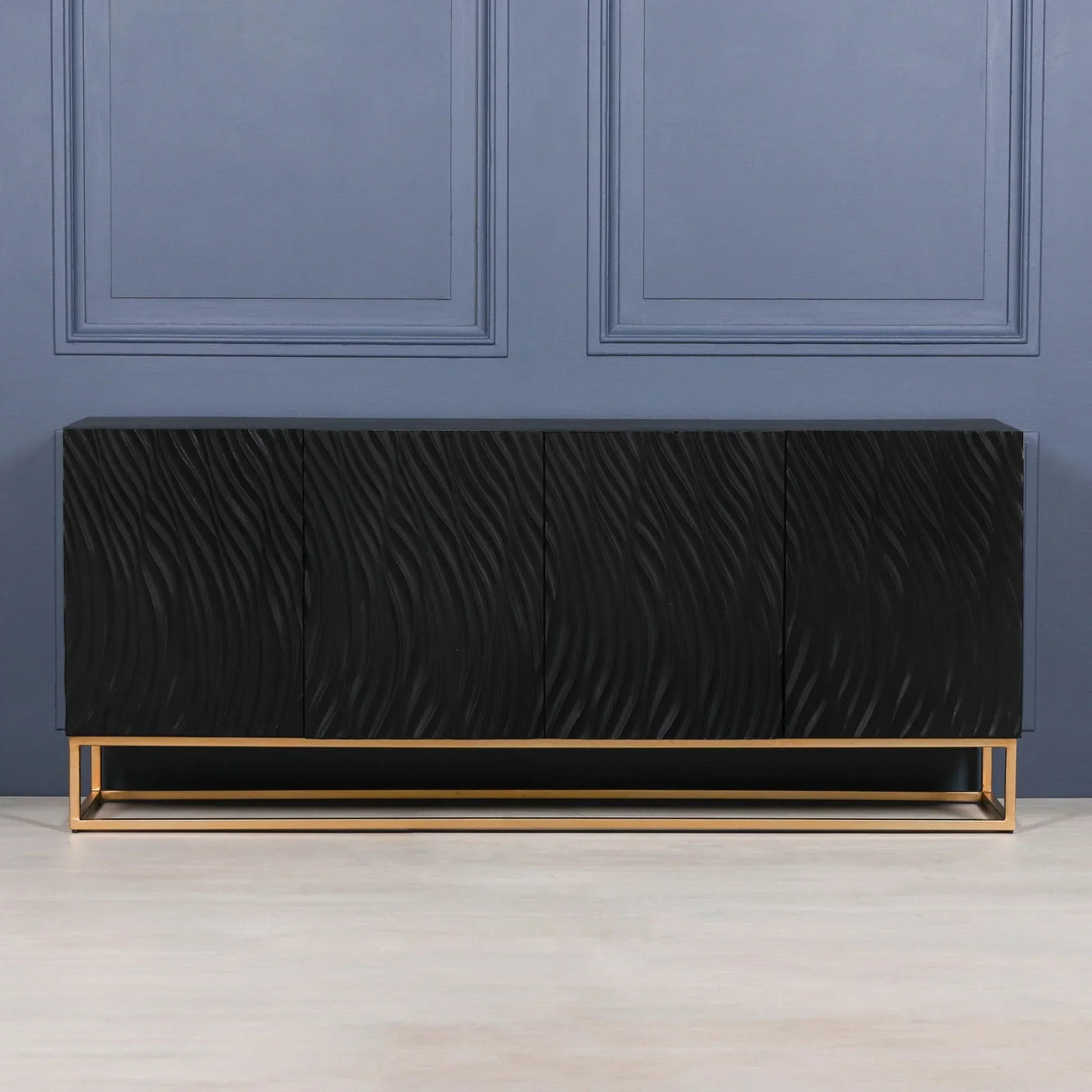 Black sideboard with textured wave pattern and gold metal base against blue wall