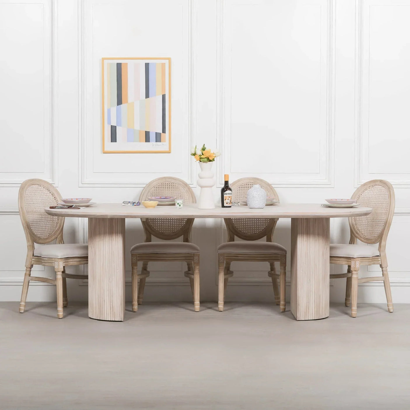 Light wood dining table with four cane back chairs set for four in modern dining room