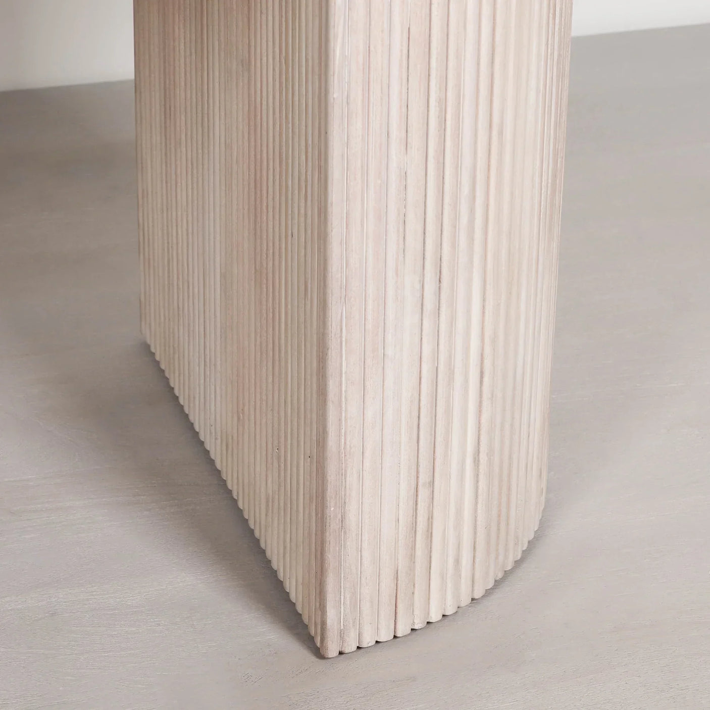 Close up of ribbed wooden table leg with light natural finish on grey floor