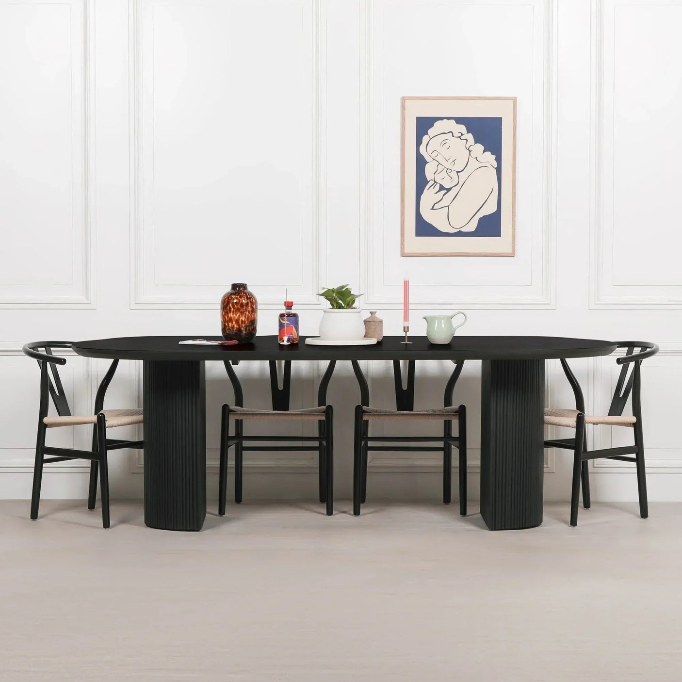 Black dining table with six chairs, decorative vases, and artwork on white panelled wall