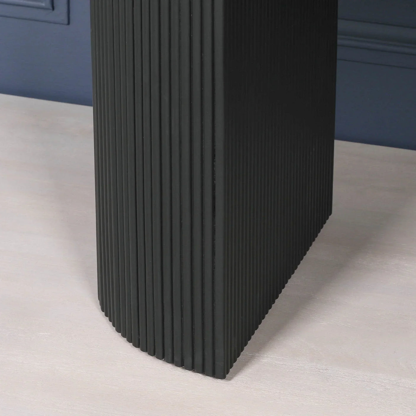 Black ribbed furniture leg with vertical grooves on light wood floor