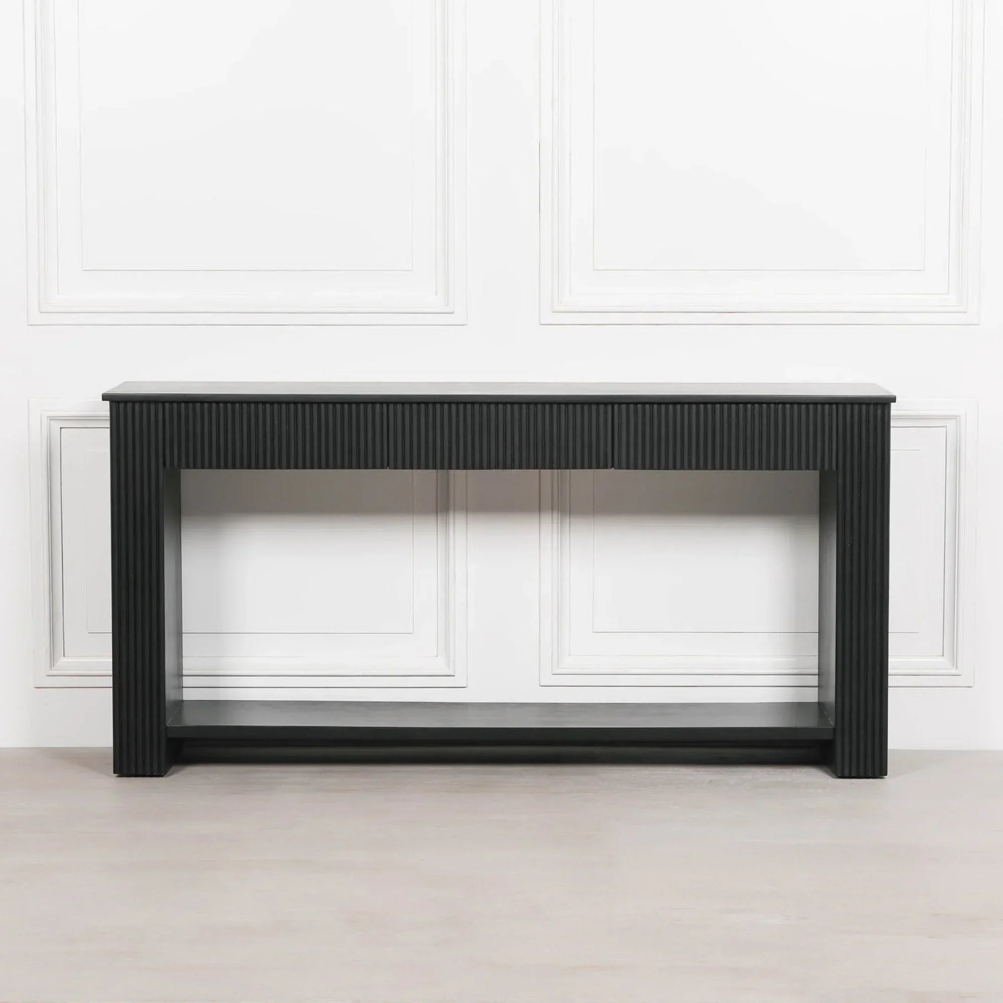 Black wood console table with grooved legs against white wall