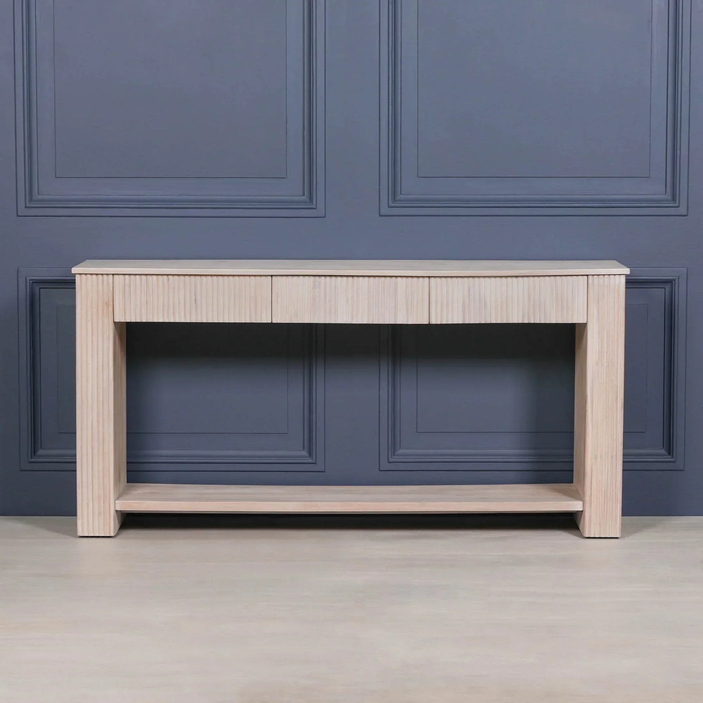 Light wood console table with fluted design and lower shelf against grey panel wall