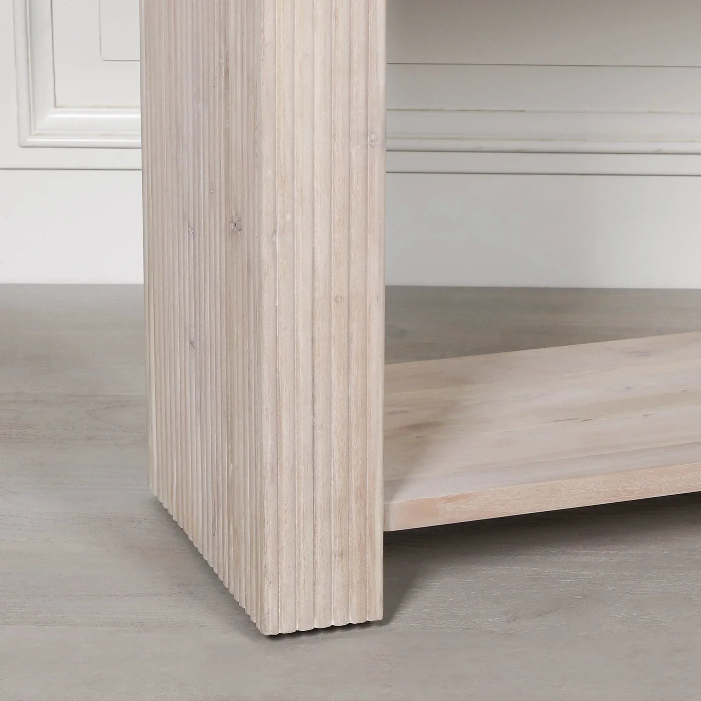 Close-up of light wood furniture leg with vertical grooves and flat base on smooth floor