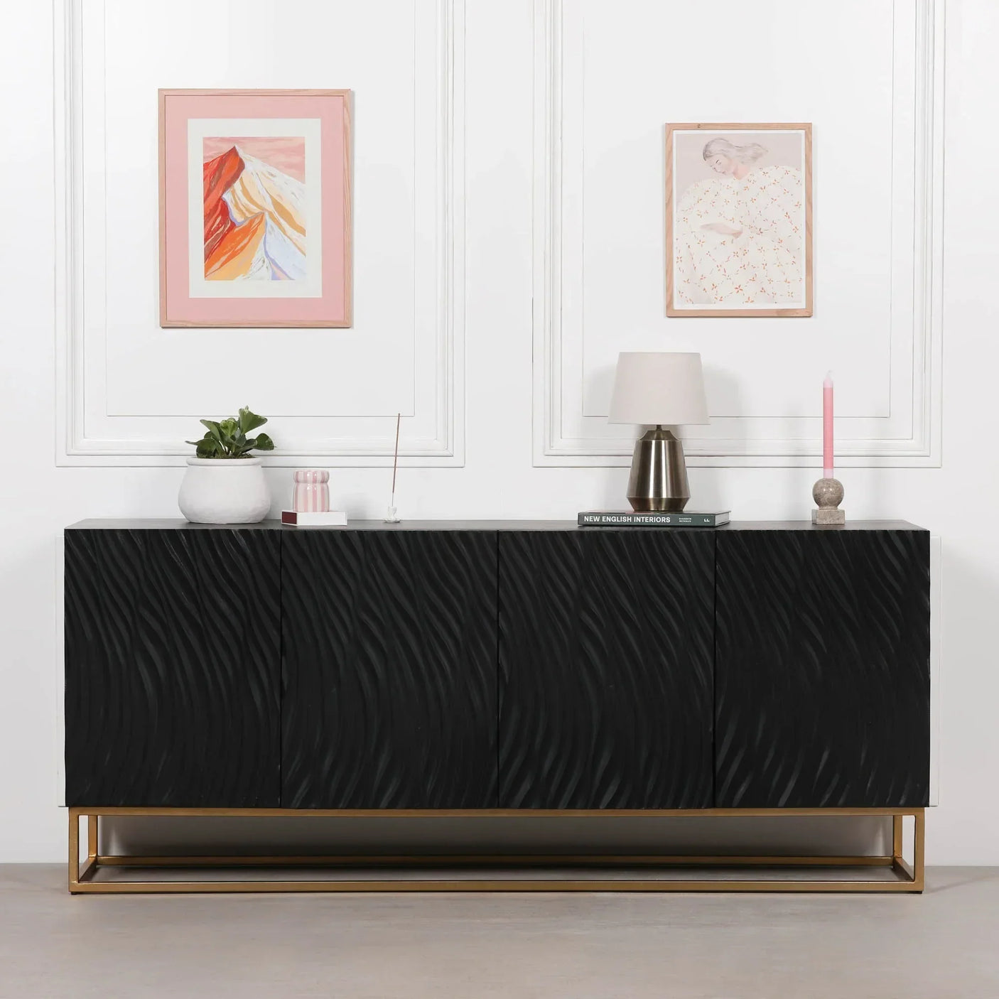 Black sideboard with textured front, gold base, and modern decor in a white room
