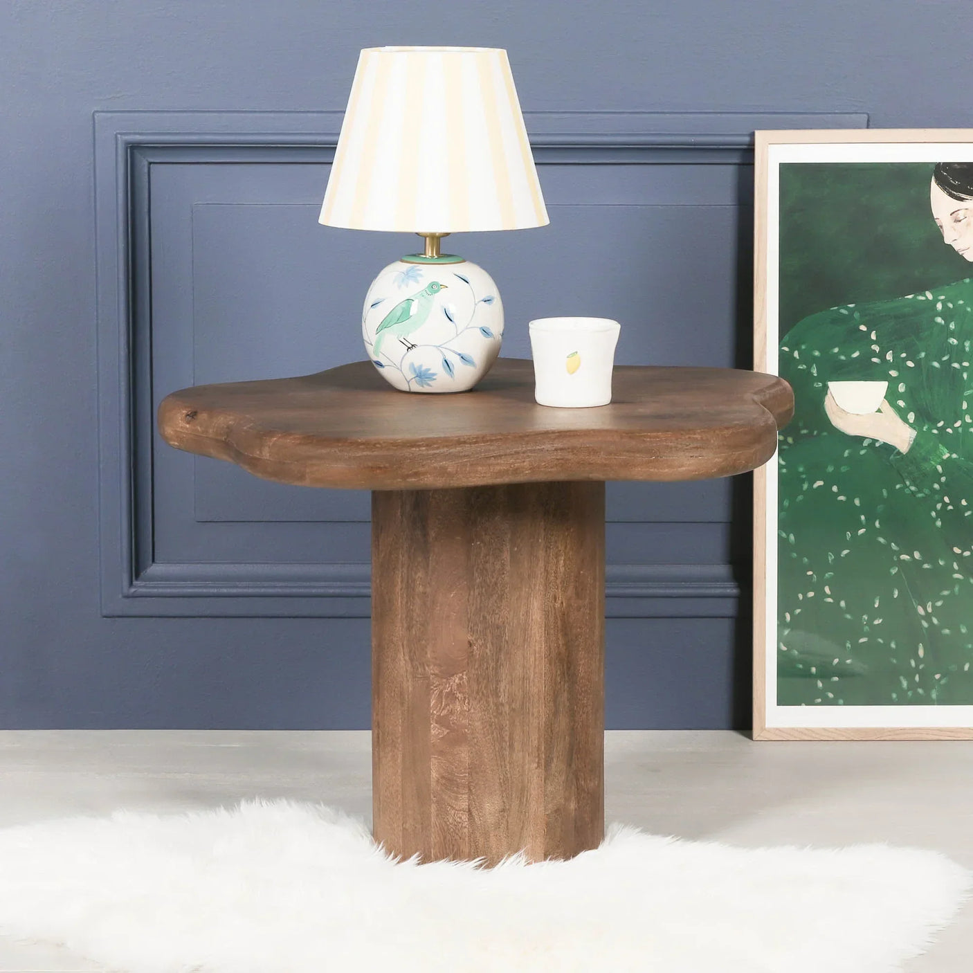 Solid wood side table with natural edge, lamp and decor against blue wall