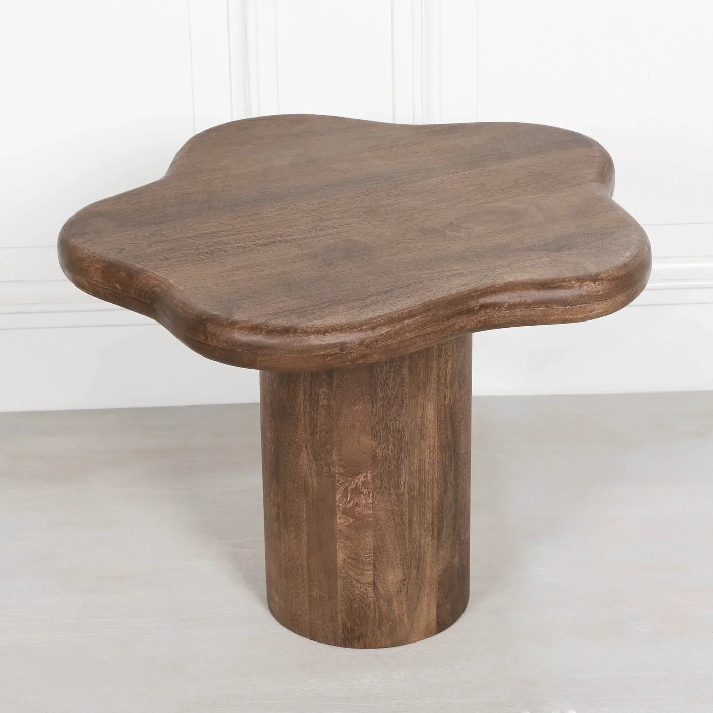 Solid wood coffee table with clover-shaped top and cylindrical base on light floor