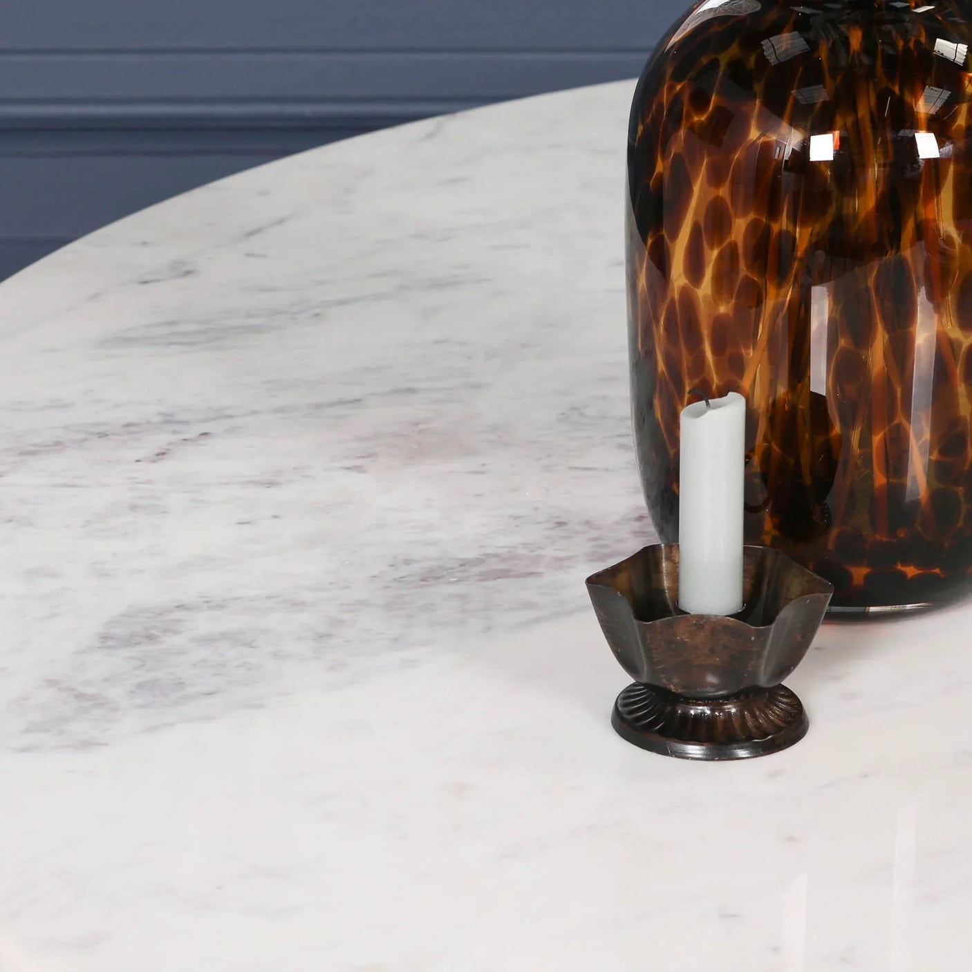 White marble dining table surface with brown vase and metal candle holder