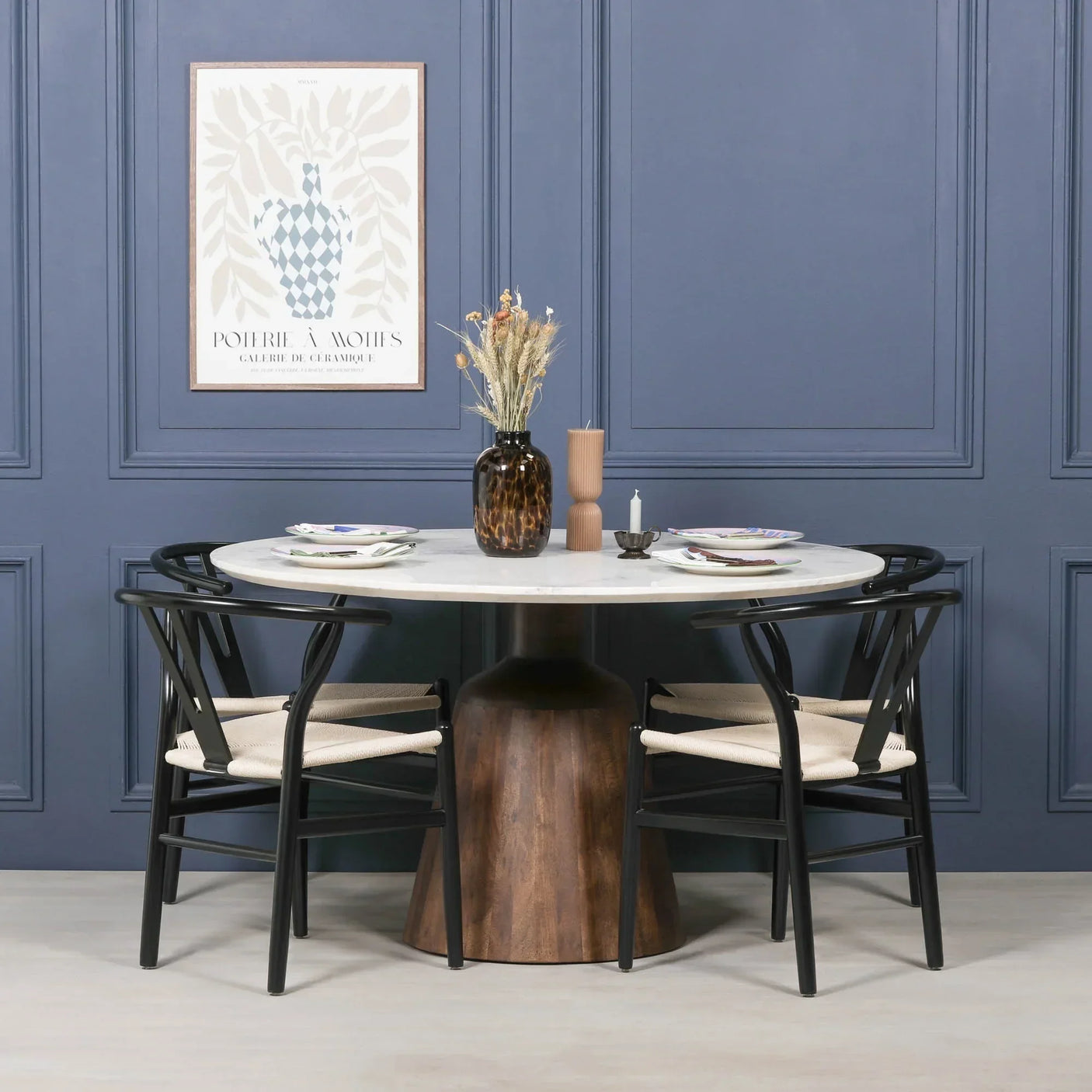 Modern round dining table with white marble top, wood pedestal base, black dining chairs