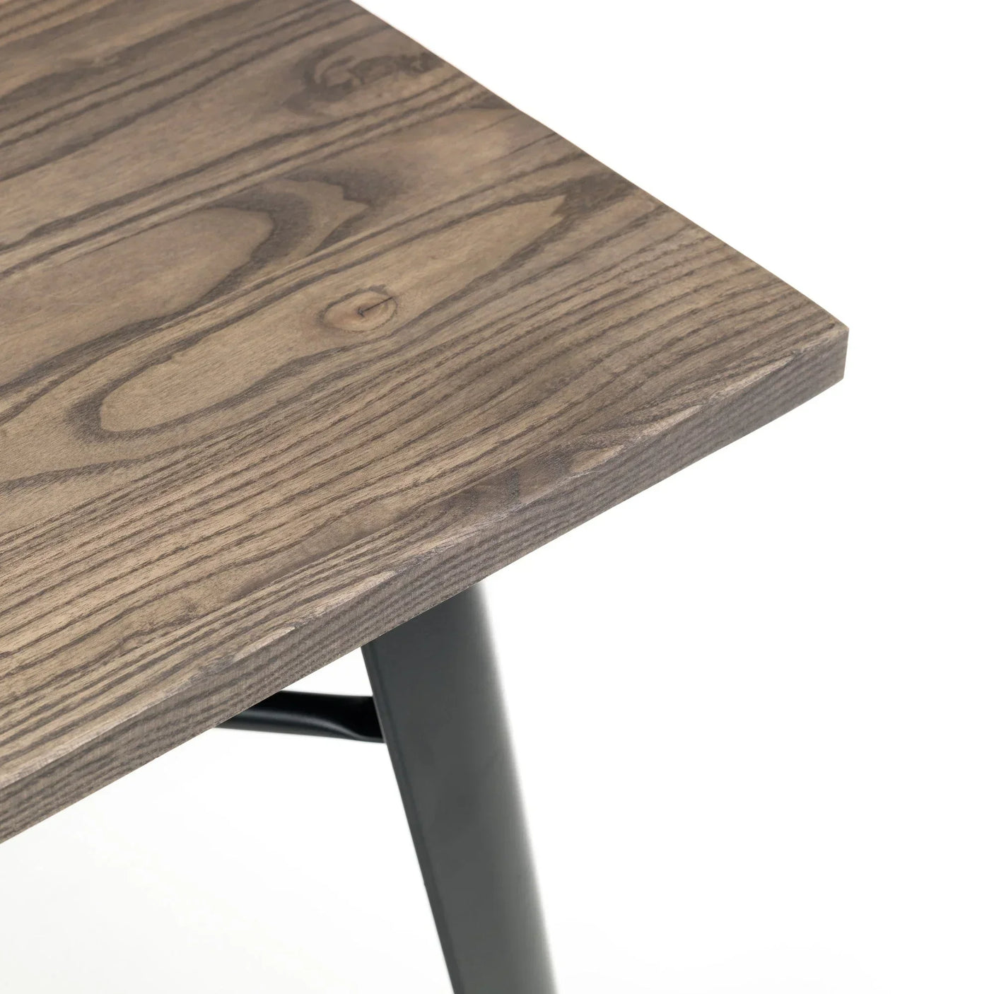 Corner detail of wood dining table with natural grain and black angled leg